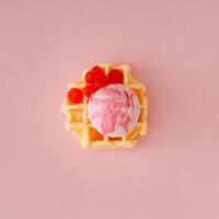 Waffle and pink ice cream with raspberry topping and fresh red berries on pastel pink background. Minimal sweet food concept. Trendy delicious dessert idea. Flat lay style. photo
