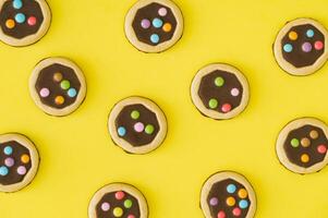 Vibrant pattern composition made of colorful cookies on a bright yellow background. Minimal sweet food concept. Fun, festive, playful and yummy layout. Biscuits aesthetic. Flat lay style. Top view. photo