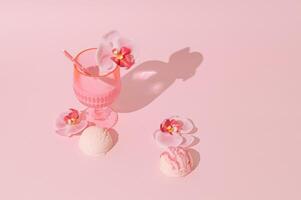 Summer scene with pink tropical drink, orchid flowers and ice cream scoops on pastel pink background. Sun and shadows. Minimal cocktail concept. Trendy summertime party idea. Summer aesthetic. photo