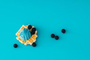 Waffle and blue ice cream with topping and fresh blueberries on light blue background. Minimal sweet food concept. Trendy delicious dessert idea. Flat lay style. photo