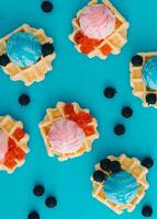 Pattern with waffles, ice cream scoops, raspberries and fresh blueberries on pastel blue background. Sweet food concept. Perfect for summer themed designs and playful backdrops. Flat lay. photo
