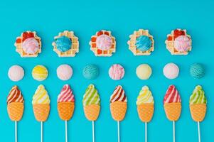 Colorful summer dessert composition with waffles, scoop of ice cream and ice cream shaped lollipops on a light blue background. Bright and vibrant colors. Flat lay style. Top view. photo