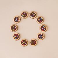 Colorful chocolate cookies on beige background. Minimal sweet food concept. Trendy yummy biscuits idea. Flat lay style. Top view banner. Creative copy space. photo