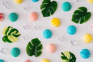 Playful and vibrant summer pattern featuring delicious ice cream scoops, tropical leaves and ice cubes on white background. A fresh and fun design that captures the essense of sunny days. Flat lay. photo