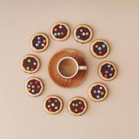 Colorful chocolate cookies with cup of coffee on pastel cream background. Minimal coffee with biscuits concept. Yummy sweet food and hot drink idea. Flat lay style. Top view. photo