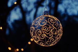 Elegant thin line silhouette of a Christmas ball hanging, illuminated by decorative lights in a winter night setting photo