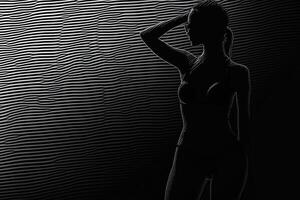 A graceful silhouette of a figure in a swimsuit striking a pose against a textured background of rippled lines photo