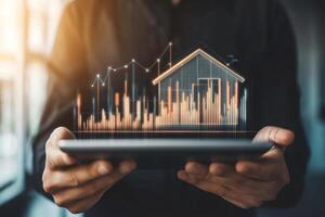 Businessman presenting digital house model on tablet with rising graphs to illustrate real estate investment growth in a modern office photo