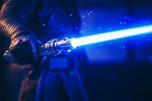 A man grips a bright blue lightsaber, showcasing power and creativity in a dynamic action pose in a dimly lit environment photo