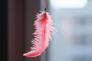 A playful pink feather cat toy teaser hanging from a string, perfect for engaging feline fun indoors photo