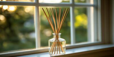 Aroma reed diffuser with rattan sticks sits on a sunlit window sill creating a relaxing ambiance in a minimalist home decor setting photo