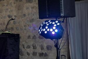 Colorful stage lighting set up for a music event in a rustic venue with stone walls photo