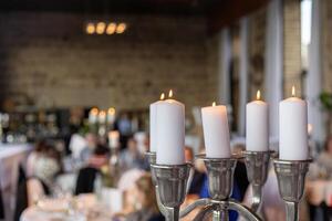 Elegant dining setup with candles at a festive gathering in a rustic venue during evening hours photo