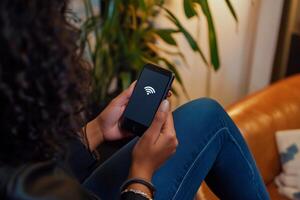 Using a smartphone to connect to Wi-Fi while relaxing on a couch in modern living room photo