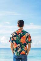 Man in floral shirt enjoys a serene beach view with clear blue skies and calm waves in the background during summer photo