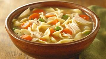 Warm chicken noodle soup with vegetables served in a rustic bowl on a wooden table photo