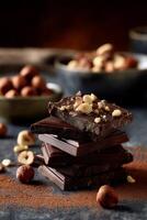 Dark chocolate stack with hazelnuts. Layers of dark chocolate bars topped with chopped hazelnuts, surrounded by cocoa powder and scattered hazelnuts photo