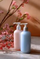 Two pump bottles of lotion, light pink and light blue, sit on a light beige surface, with a branch of pink blossoms in the background photo