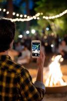 Man taking photo of campfire at night