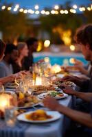 Outdoor dining with friends at twilight. A long table is set with food and drinks under string lights, by a pool. Group of diverse adults enjoy a meal together, focused on the hands and dishes photo
