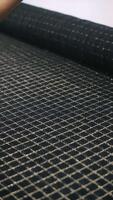 Hand unrolling black fabric with stitched grid pattern video