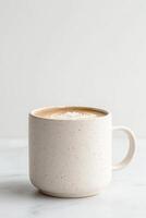 Coffee latte art in ceramic mug. Warm drink with leaf design. Marble surface. Simple background. Creamy coffee photo
