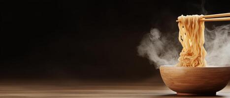 Steaming noodles lifted with wooden chopsticks above a wooden bowl on a brown table. Dark background shows steam rising from the hot noodles photo