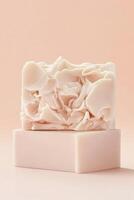 Two pale soaps sit stacked. Top soap has rough texture. Bottom soap is plain. Neutral background. Clean product photography. Minimalist design photo