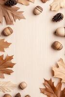 Dried autumn leaves and acorns border a beige surface. Oak leaves and pine cones frame the textured background. Natural earthy tones give soft fall appearance. photo