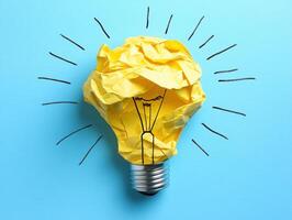 Crumpled paper light bulb concept on blue background photo