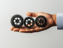 Holding three interconnected gears in a hand against a plain background during a creative brainstorming session photo