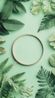 Green leaves and ferns border light green surface. Round frame in center. Natural botanical elements. Flat lay composition. Copy space inside frame. photo