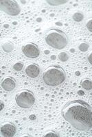 Water droplets and bubbles form white textured surface. Close view of various sizes of water pearls. Abstract nature background with light reflection. Freshness concept. photo