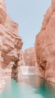 Desert canyon landscape with turquoise water flowing over a dam between tall textured sandstone cliffs under a clear blue sky during daytime photo
