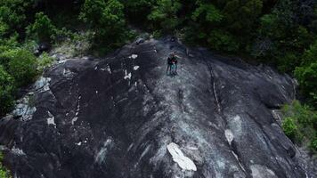 Aerial drone footage capturing lush jungles and rocky landscapes of Koh Phangan island with a family enjoying nature on a large smooth rock surrounded by greenery video