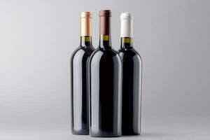 Three wine bottles with different colored capsules are standing on gray background photo