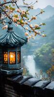 Glowing chinese lantern illuminating foggy valley with blooming tree branch in the foreground photo