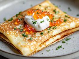 Delicious pancake dish with caviar and sour cream served on a plate photo