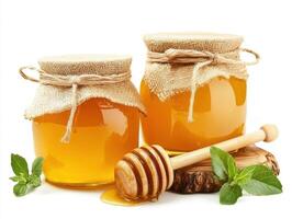 Two jars of golden honey with burlap coverings sit on a wooden surface photo