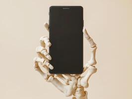 Skeleton hand holds smartphone against a plain background photo