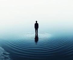 Person standing in calm water creating ripples at dawn photo
