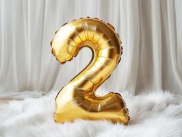 Golden number two balloon on soft white fabric background photo