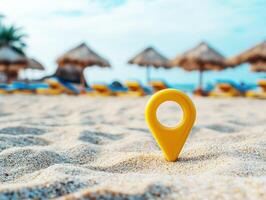 Yellow location marker on sandy beach with umbrellas in background photo