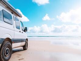 Van parked on sandy beach under bright sky with fluffy clouds photo