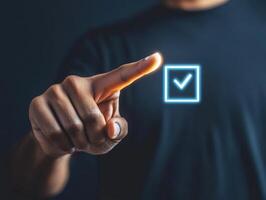 Hand interacting with digital checkmark symbol on dark background representing confirmation or approval photo