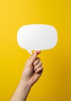 Hand holding empty speech bubble on yellow background photo