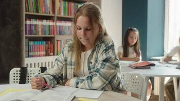 Teen girl pupil student teenager studying at classroom child kid reading book learn prepare lesson study in school education academy library happy cheerful schoolgirl portrait looking at camera smile video