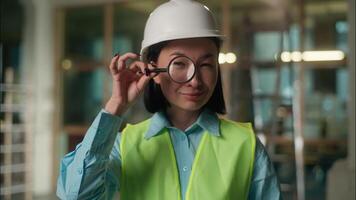 sorridente ásia construtor chinês menina arquiteto engenheiro investigador japonês coreano mulher olhando através lupa visão teste espião Veja com ampliação vidro grande ampliado olho procurando investigando video