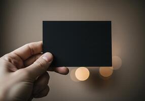 A person holding up a black card in front of a blurred background photo