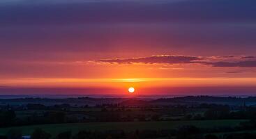 A sunset over a field with a plane flying over it photo